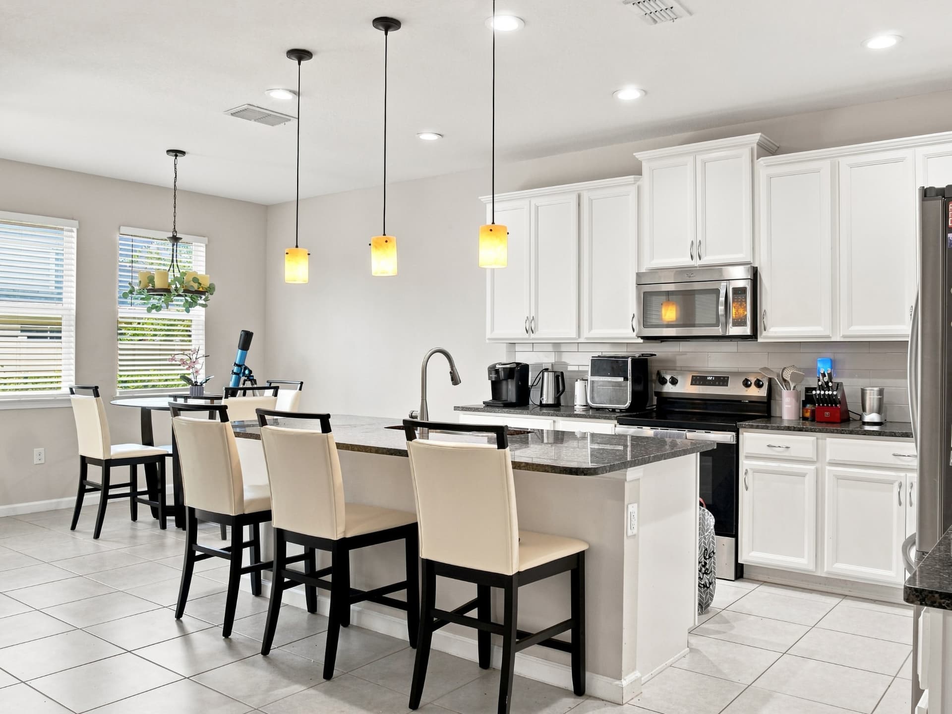 Bright open-concept kitchen with granite island, pendant lighting and dining area